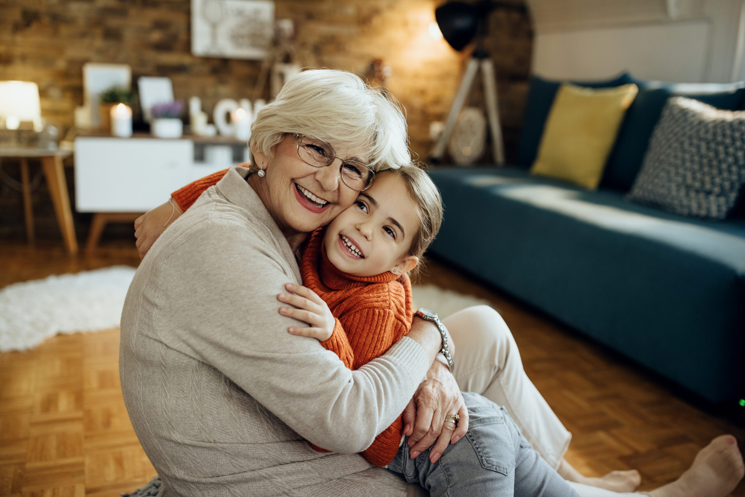 Happy little girl and her grandmother embracing while spending time together at home.