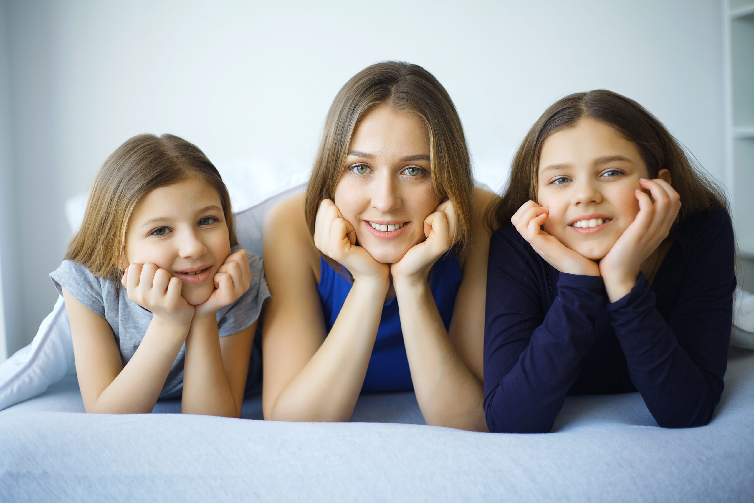 Woman and young girl lying in bed smiling.